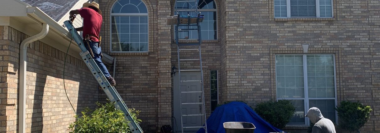 Two men working on a house with a ladder.