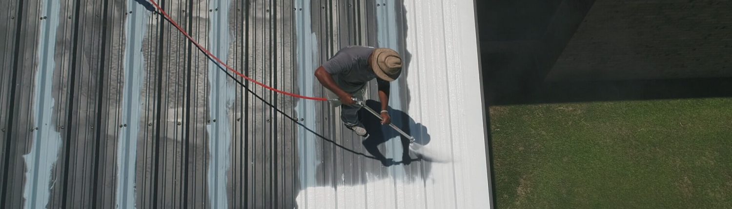 A man painting the roof of a house.