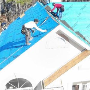 Two men working on a roof of a house.